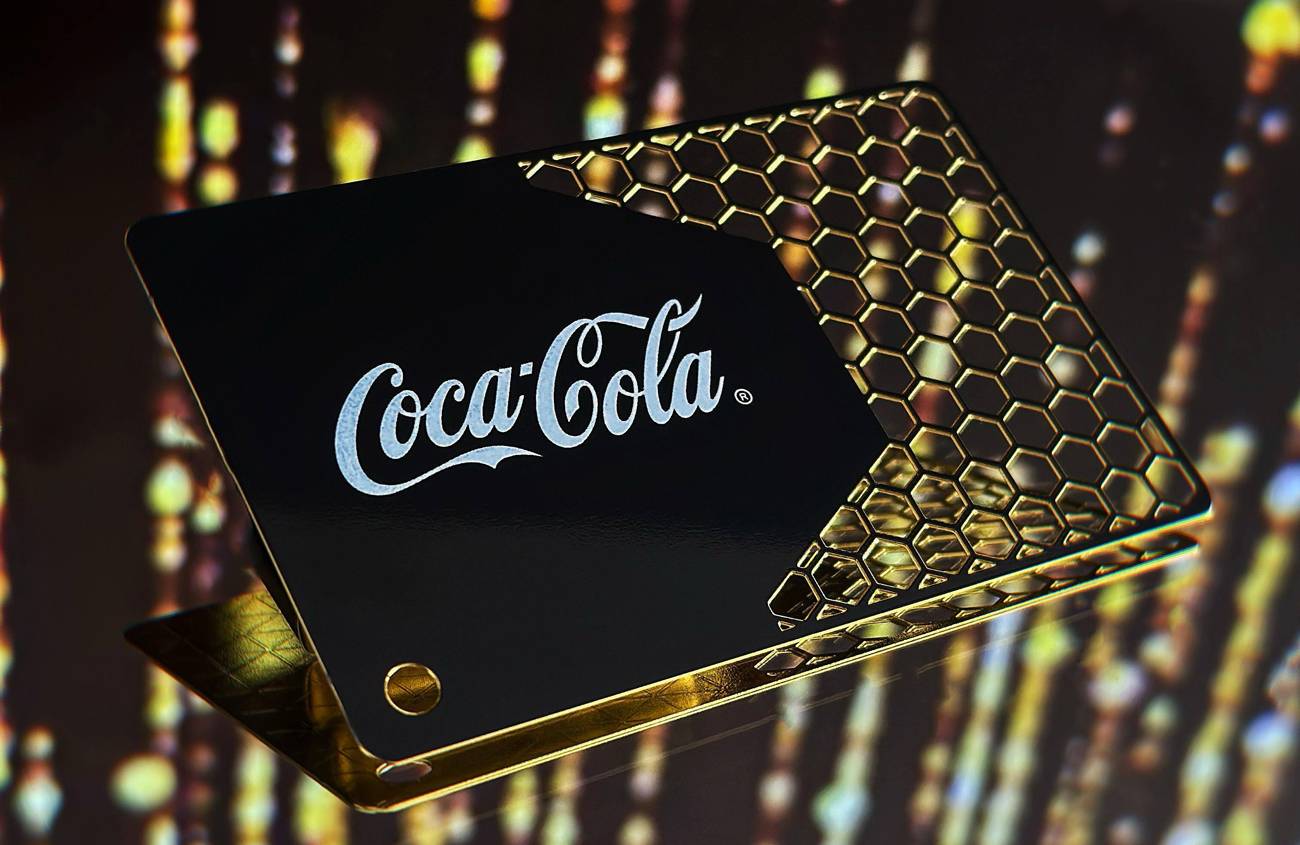 Melna un zelta Coca-Cola metāla vizītkarte ar šūnveida izgriezumiem