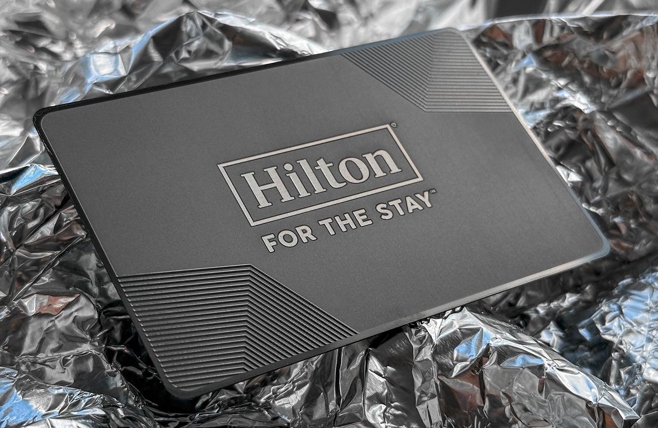 Tumša Hilton metāla karte ar gravētu logotipu sudraba iepakojumā
